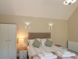 A bedroom with a double bed green cushions bedside tables a wardrobe and wall lights at Beaconsfield Cottage in Burniston near Scalby