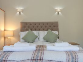 A bed with a tufted headboard two green pillows white towels and bedside lamps at Beaconsfield Cottage in Burniston near Scalby