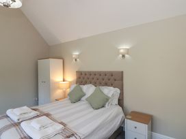A bedroom with a double bed two green cushions bedside tables lamps and a white wardrobe at Beaconsfield Cottage in Burniston near Scalby