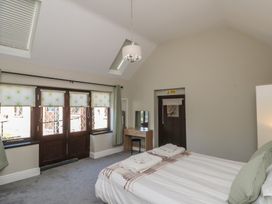 A bedroom with a bed, desk, chair, skylights, windows with blinds, and a door at Beaconsfield Cottage in Burniston near Scalby