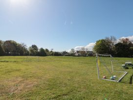 A grassy field with two soccer goals three balls near a goal and houses with trees in the background at Beaconsfield Cottage in Burniston near Scalby