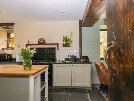 A kitchen with a wooden table and flower vase at Ewedale Farm in Pennington near Ulverston