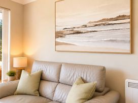 A living room with a sofa and wall art at 6 Coedrath Park - Swn y Mor in Saundersfoot