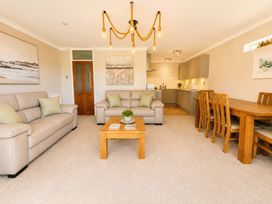 A living room with a sofa, coffee table, and dining area at 6 Coedrath Park - Swn y Mor Saundersfoot