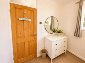 A hallway with a door and dresser at 6 Coedrath Park - Swn y Mor Saundersfoot