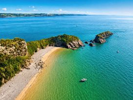 A beach with rocks and a boat at 6 Coedrath Park - Swn y Mor in Saundersfoot