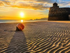 A buoy on the beach with a fort at sunset at 6 Coedrath Park - Swn y Mor in Saundersfoot