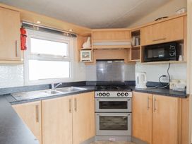 A kitchen with wooden cabinets a double sink a stove microwave and kettle at The Cabin in Occumster near Lybster