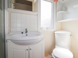 A bathroom with a sink and cabinet a window and a toilet at The Cabin in Occumster near Lybster