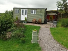A shepherds hut with chairs and garden space at The Journeyman Luxury Shepherds Hut in Barnoldswick