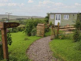 An outdoor view of a shepherds hut with a path and gate at The Journeyman Luxury Shepherds Hut in Barnoldswick