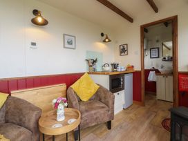 A living room with a sofa and kitchenette at The Journeyman Luxury Shepherds Hut in Barnoldswick