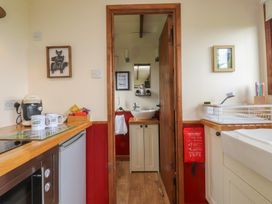A kitchen with refrigerator and sink leading to a bathroom at The Journeyman Luxury Shepherds Hut in Barnoldswick