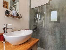 A bathroom with a wash basin and shower at The Journeyman Luxury Shepherds Hut in Barnoldswick