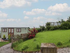 An outdoor area with a shepherd's hut and grassy landscape at The Journeyman Luxury Shepherds Hut Barnoldswick