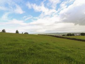 A field with grass and trees under a cloudy sky at The Journeyman Luxury Shepherds Hut in Barnoldswick