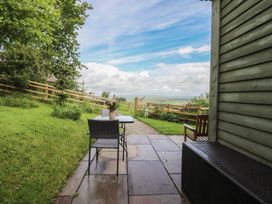 An outdoor area with a table and chairs overlooking greenery at The Journeyman Luxury Shepherds Hut in Barnoldswick