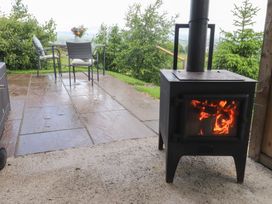 An outdoor area with a wood stove and seating at The Journeyman Luxury Shepherds Hut in Barnoldswick