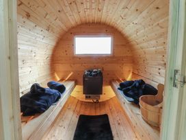 A sauna with wooden benches and a wood stove at The Journeyman Luxury Shepherds Hut in Barnoldswick