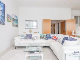 A living room with a white sectional sofa decorated with patterned pillows and a glass coffee table at Bay Sea View in Torquay