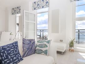 A living room with patterned cushions on a white sofa and windows overlooking a balcony with sea view at Bay Sea View in Torquay