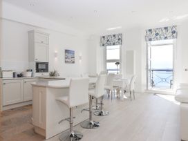 A kitchen and dining area with white chairs a countertop and a view of the sea at Bay Sea View in Torquay