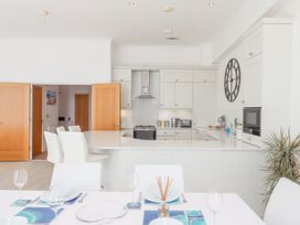 A white kitchen with bar stools and a dining table set with plates and glasses at Bay Sea View in Torquay