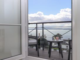 A balcony with two chairs and a small table with two mugs overlooking the sea at Bay Sea View in Torquay