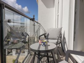 A balcony with glass railing a round table two chairs and two mugs at Bay Sea View in Torquay