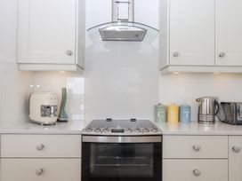 A kitchen countertop with a stove oven range hood utensil holder canisters electric kettle and toaster at Bay Sea View in Torquay