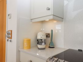 A kitchen countertop with a yellow container a cream coffee machine and kitchen utensils at Bay Sea View in Torquay