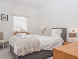 A bedroom with a bed with pillows and rolled towels a window with blinds a chair a bedside table with a lamp and a dresser with a mirror at Bay Sea View in Torquay