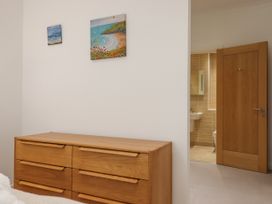 A wooden dresser with six drawers and two paintings on the wall next to a wooden door leading to a bathroom at Bay Sea View in Torquay