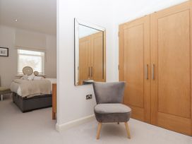 A bedroom with a bed towels and mirrors a grey chair wooden wardrobe doors and a wall mirror at Bay Sea View in Torquay