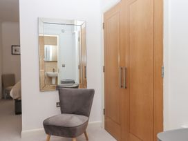 A grey upholstered chair in front of a wall mirror next to a wooden double closet door at Bay Sea View in Torquay