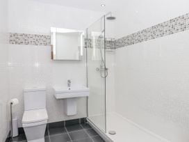 A bathroom with a toilet a sink a glass-enclosed shower and a mirror at Bay Sea View in Torquay