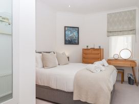 A bedroom with a bed and two pillows a dresser a vanity with two round mirrors and a window with a blind at Bay Sea View in Torquay