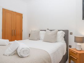 A bedroom with a double bed two pillows bedside table with a lamp and wooden closet Bay Sea View in Torquay