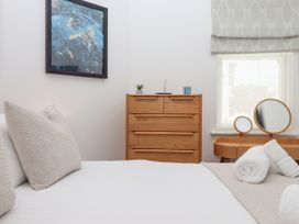 A bedroom with a bed with pillows a wooden dresser a vanity table with mirrors and rolled towels at Bay Sea View in Torquay