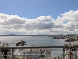 A view of a bay with houses and trees along the shore under a cloudy sky at Bay Sea View in Torquay