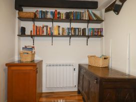 A snug with bookshelves and wooden furniture at Vi’s Valley View in Pentewan