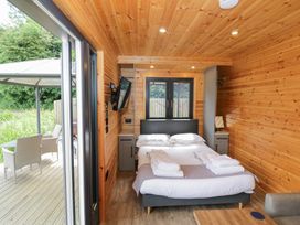A bedroom with a bed and television at Maple Lodge at Bridge Lake Farm & Fishery Chacombe