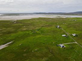 An aerial view of green landscape with scattered houses and a coastline at Taigh Gorm Baleshare near Balivanich