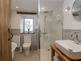 A bathroom with a toilet near a window a glass shower enclosure and a sink on a wooden countertop at Style Cottage in Keswick