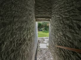 A stone corridor with a wooden handrail leading to a garden at Style Cottage in Keswick