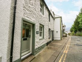 A stone exterior cottage with a green door and windows along a narrow street at Style Cottage in Keswick