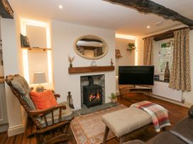A living room with a rocking chair a TV and a fireplace at Style Cottage in Keswick