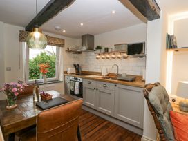A kitchen with wooden countertops and gray cabinets next to a dining table with leather chairs at Style Cottage in Keswick