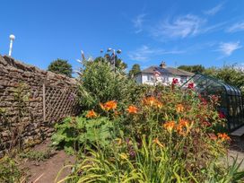A garden with flowers and a greenhouse at Glen Lea in Giggleswick, Settle