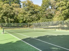 A tennis court with a net and racquets at The Cottage in Wimborne Minster